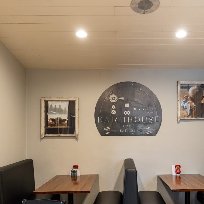 Interior of Farmhouse Cafe with booth seating, wooden tables, and rustic wall decor.